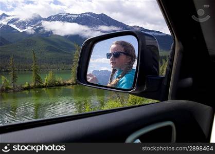 Reflection of girl on the side view mirror of a car, Jasper National Park, Alberta, Canada
