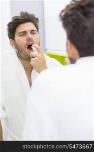 Reflection of man spraying medicine in mouth