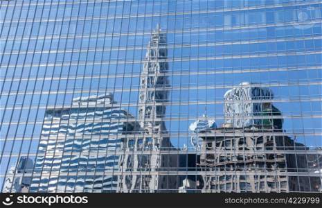 Reflection of old and new buildings in Chicago in the blue windows of a skyscraper opposite