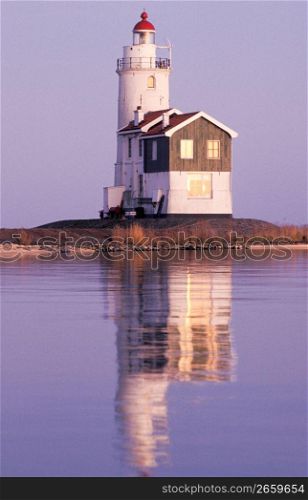 Reflection of old-fashioned lighthouse in calm ocean waters