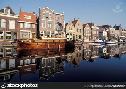 Reflection of old-fashioned wooden boat mooring on still canal in quaint village