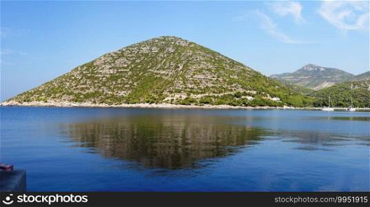 Reflection of picturesque hill in the sea. Sea coast of Peljesac peninsula in Croatia near Prapratno
