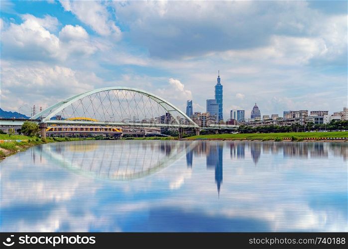Reflection of river and Second MacArthur Bridge at Taipei Downtown, Taiwan. Financial district and business centers in smart urban city. Skyscraper and high-rise buildings at noon.