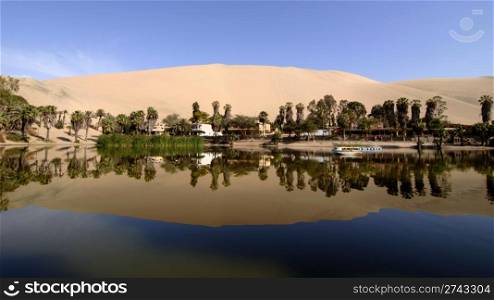 reflection of sand dunes in oasis lake