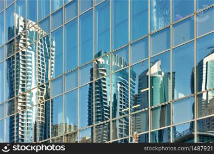 Reflection of skyscrapers in the glass wall of modern tower - architectural background