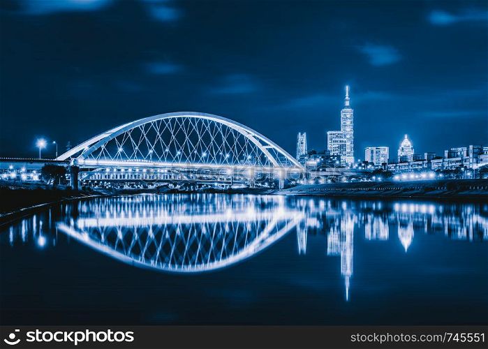 Reflection of Taipei bridge in downtown, Taiwan. Financial district and business centers in smart urban city. Skyscraper and high-rise buildings at night.