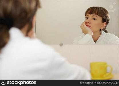 Reflection of the girl in a mirror. White bathrobe, reflective a pose