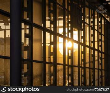 Reflection of the setting sun in the fully glazed facade of a high-rise building