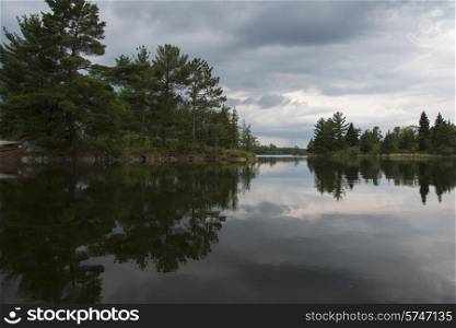 Reflection of trees and clouds in a lake, Lake of The Woods, Ontario, Canada