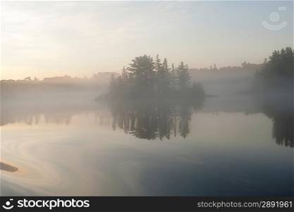 Reflection of trees in water during fog, Lake of the Woods, Ontario, Canada