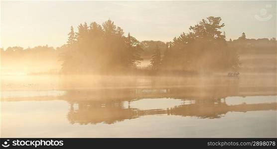 Reflection of trees in water during fog, Lake of the Woods, Ontario, Canada