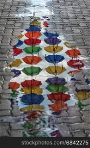 Reflection of umbrellas in a puddle on the street. Umbrella passage.