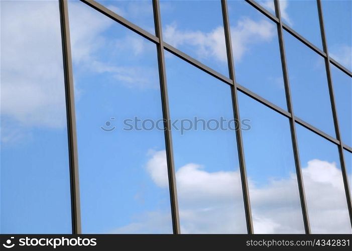 Reflection of white clouds and blue sky in the windows of the modern building