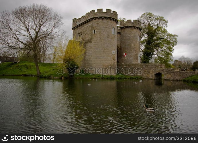 Reflection of Whittington Castle in the moat with ducks swimming by