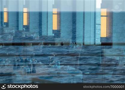 Reflections of ocean in windows around modern restaurant on luxury cruise ship at sea. Reflection of ocean in windows of restaurant of cruise ship