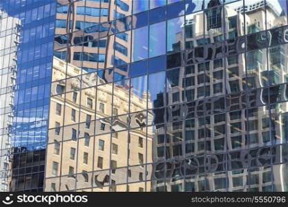 Reflections of old buildings in the windows of modern city office building tower