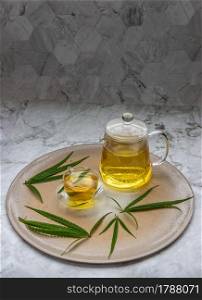 Refreshing and enjoy with A cup of Cannabis herbal tea and Stem with green marijuana leaves on marble table for medical purposes for sleep and anxiety. Herbal tea and healthy drinks concept. Copy space, Selective focus.