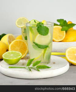 refreshing drink lemonade with lemons, mint leaves, lime in a glass , next to the ingredients for making a cocktail