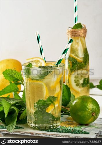 refreshing drink lemonade with lemons, mint leaves, lime in a glass , next to the ingredients for making a cocktail