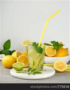 refreshing drink lemonade with lemons, mint leaves, lime in a glass , next to the ingredients for making a cocktail
