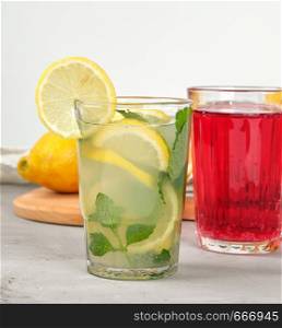 refreshing drink lemonade with lemons, mint leaves, lime in a glass and red berry lemonade, close up