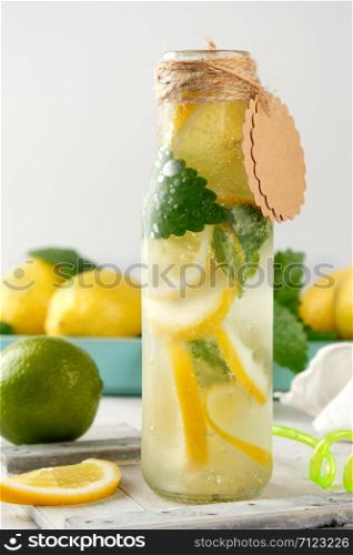 refreshing drink lemonade with lemons, mint leaves, lime in a glass bottle, next to the ingredients for making a cocktail