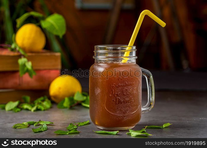 Refreshing lemon iced tea in glass cup on dark background