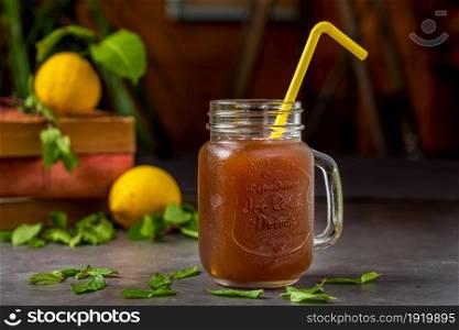 Refreshing lemon iced tea in glass cup on dark background