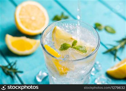 Refreshing lemonade in glass with lemon on wooden table