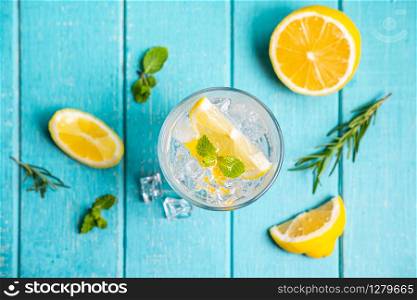 Refreshing lemonade in glass with lemon on wooden table