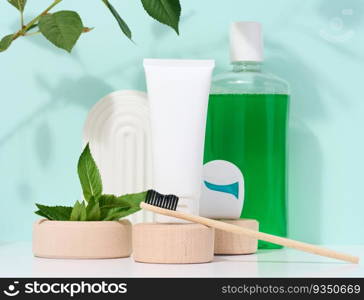 Refreshing mouthwash in a transparent plastic bottle and dental floss, white tube on a blue background