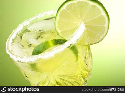 Refreshing summer cocktail drink with limes and ice isolated on green gradient background with copy space.