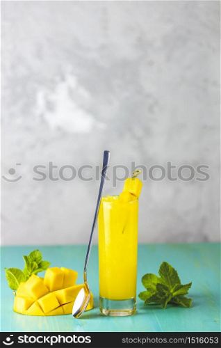 Refreshing summer cocktails made of mango, cold drink or a drink with ice on a blue gray background. Fresh summer ice cold mango cocktail or juice with mint and mango fruit.