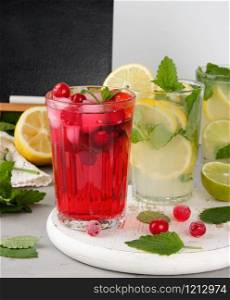 refreshing summer drink of strawberries and cranberries on a white wooden board, behind it are yellow lemons and green mint leaves