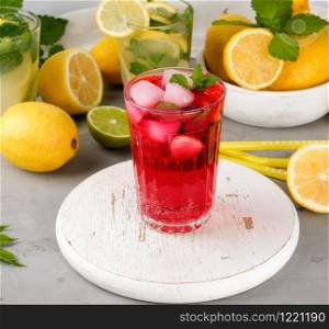 refreshing summer drink of strawberrieson a white wooden board, behind it are yellow lemons and green mint leaves