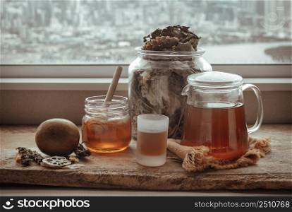 Refreshing with Chinese herbal tea (Jub Lieng) served with honey on old wooden table with city view. Herbal plant and healthy drinks concept, Selective focus.