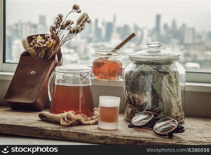 Refreshing with Chinese herbal tea  Jub Lieng  served with honey on old wooden table with city view. Herbal plant and healthy drinks concept, Selective focus.