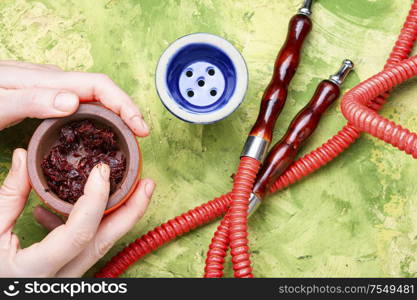 Refueling tobacco shisha with fruit tobacco.Detail of a hookah in hands.Oriental smoking hookah.. Preparation of a smoking hookah