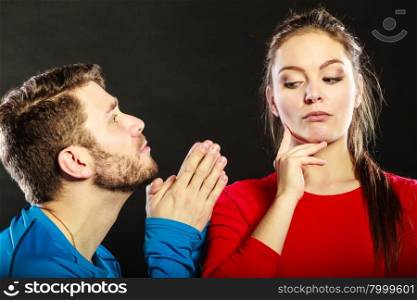 Regretful man husband apologizing woman wife.. Husband apologizing wife. Man asking woman for forgivness. Boyfriend trying to convince girlfriend. Conflicted couple in studio on black. Relationship problem.