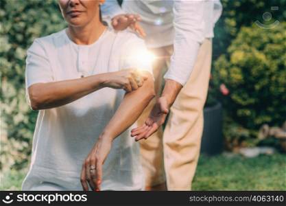 Reiki Class. Reiki instructor therapist holding hands over the elbow of a patient . Reiki Class. Elbow Healing Treatment Lesson