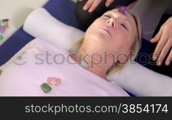 Reiki therapy with girl working as spirit healer, arranging crystals and gemstones on female client for treatment. Sequence