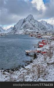Reine fishing village on Lofoten islands with red rorbu houses in winter with snow. Norway. Reine fishing village, Norway