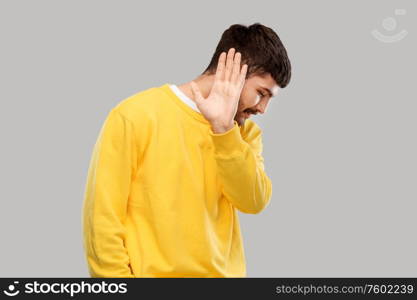 rejection and people concept - serious young man in yellow sweatshirt showing refusal gesture over grey background. serious young man showing refusal gesture