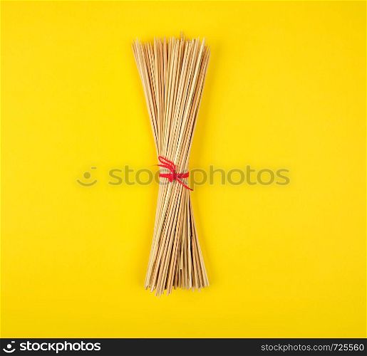 related sharp bamboo sticks barbecue on a yellow background, top view