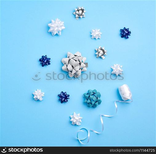 related white, blue and gray bows for gifts on a blue background, decor for decorating gifts, top view