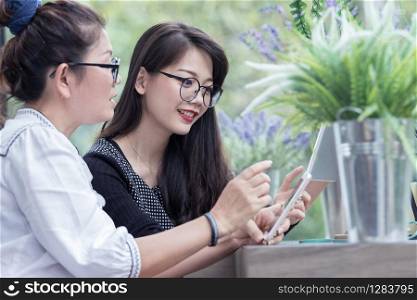 relation of two younger asian woman talking with smart phone in hand happiness smiling face