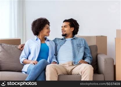 relations, communication and people concept - happy couple sitting on sofa and talking at home. happy couple sitting on sofa and talking at home