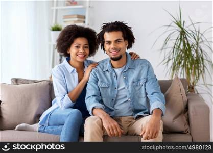 relations, communication and people concept - happy couple sitting on sofa at home. happy couple sitting on sofa at home