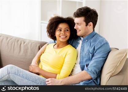 relations, love and people concept - happy smiling international couple hugging at home. happy smiling international couple at home