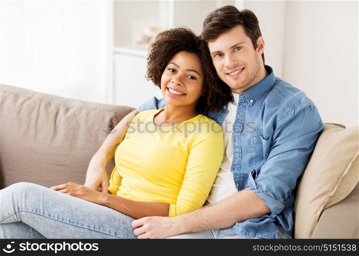 relations, love and people concept - happy smiling international couple hugging at home. happy smiling international couple at home